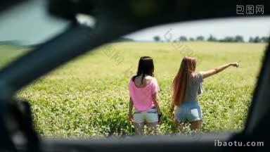透过车窗，看到两个迷人的女人站在花田在一个迷人的夏日